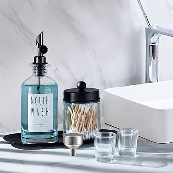 Munstölj i glasflaska och bomullspinnar på ett handfat i badrummet.