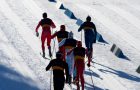 A group of men head to the finish line in a cross country ski race.