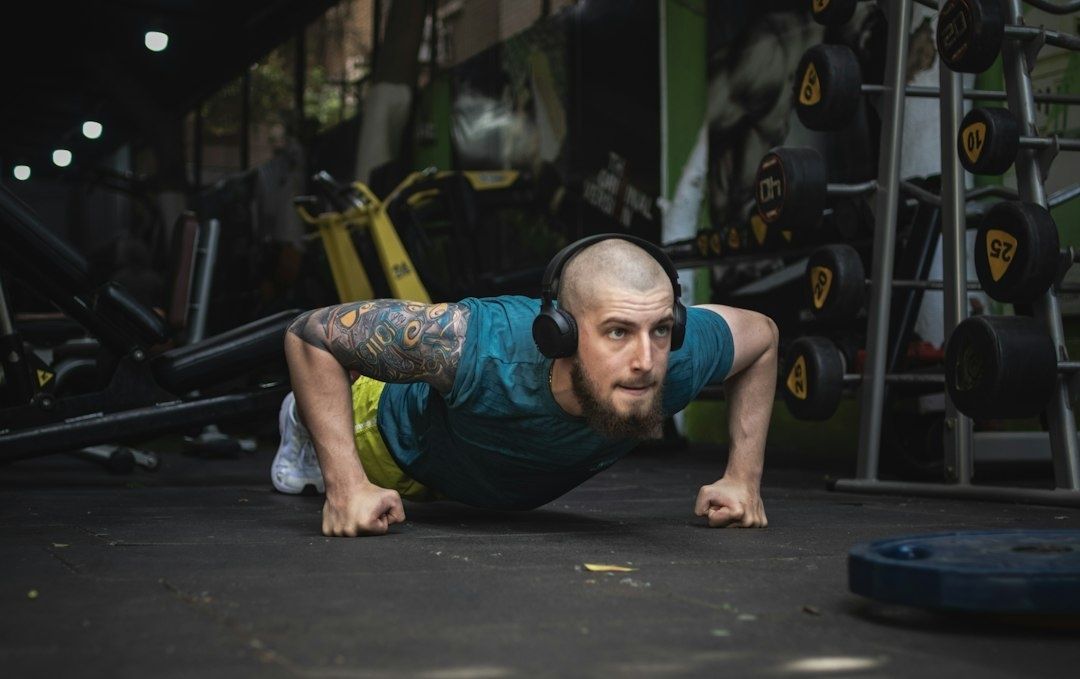 Man gör en smal armhävning på gymmets golv med hörlurar